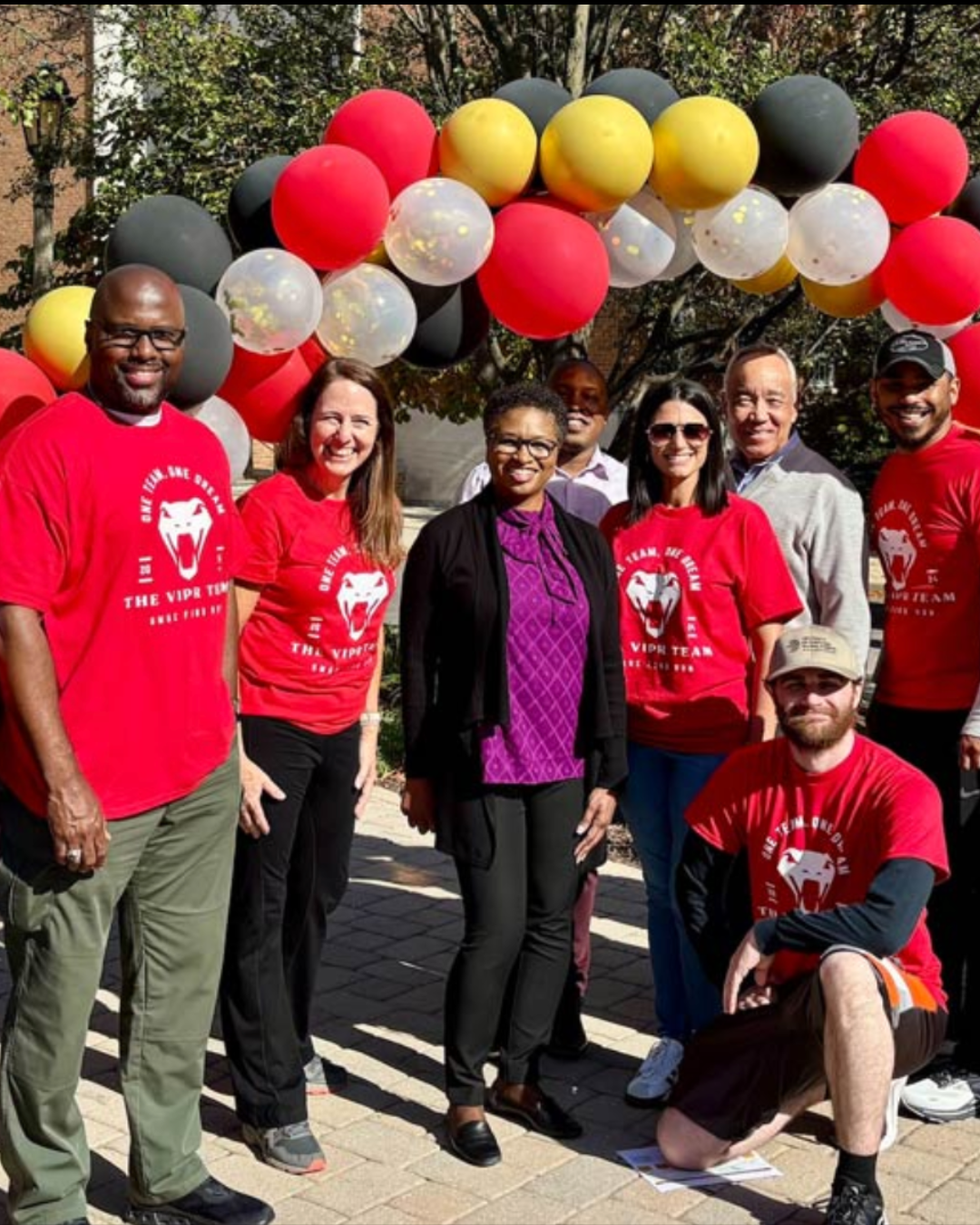 UMGC staff members posing with the FUNd Run Race Starts Here Sign